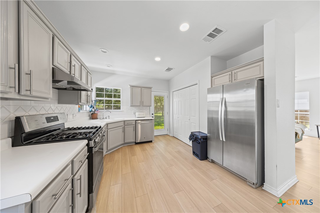 1710 Greening Way Leander, TX 78641 - Photo 13 of 47 a kitchen with stainless steel appliances a refrigerator a sink a stove white cabinets and wooden floor