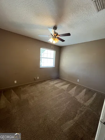 an empty room with a ceiling fan and window
