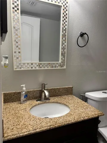 a bathroom with a granite countertop sink toilet and a mirror