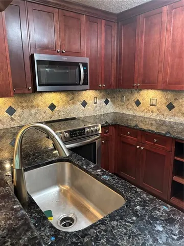 a kitchen with granite countertop a stove and a sink