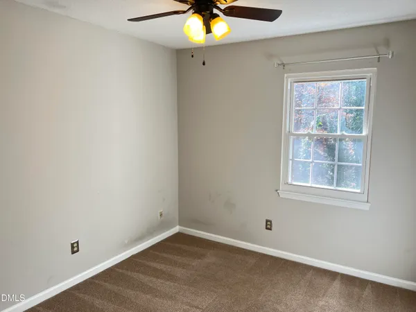 an empty room with window and a chandelier fan