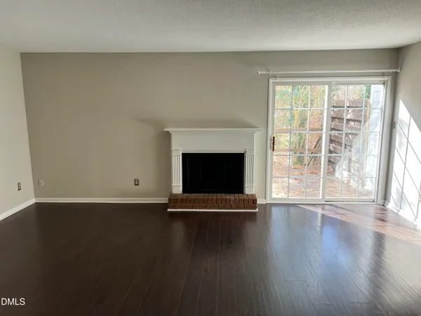 an empty room with wooden floor and fireplace