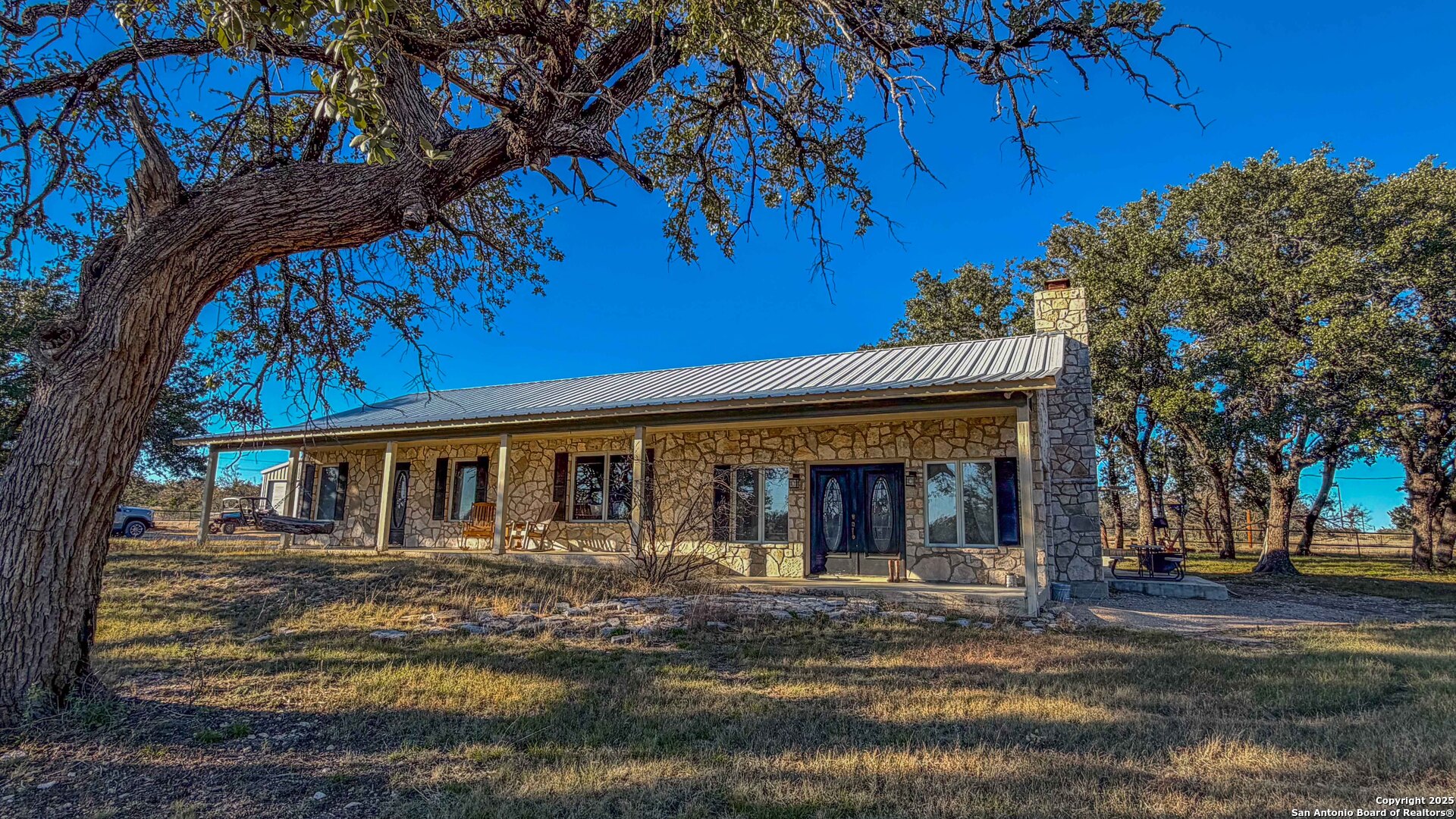 1950 Tolles Road Menard, TX 76859 - Photo 8 of 54 a view of a white house with large windows next to a road and palm trees