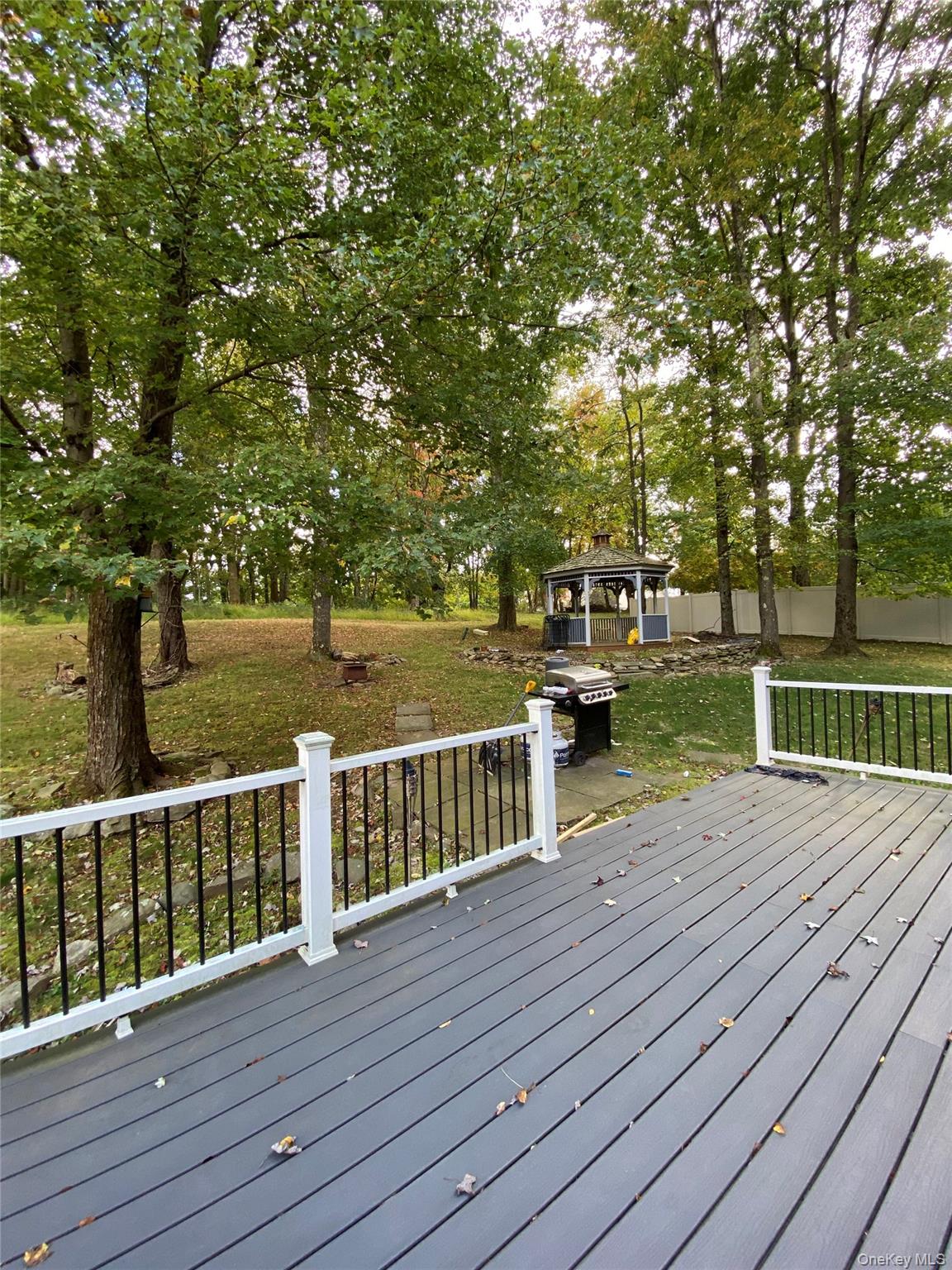 31 Denman Road Middletown, NY 10940 - Photo 18 of 18 The property features a spacious outdoor deck with white railings, overlooking a large yard with mature trees and a gazebo