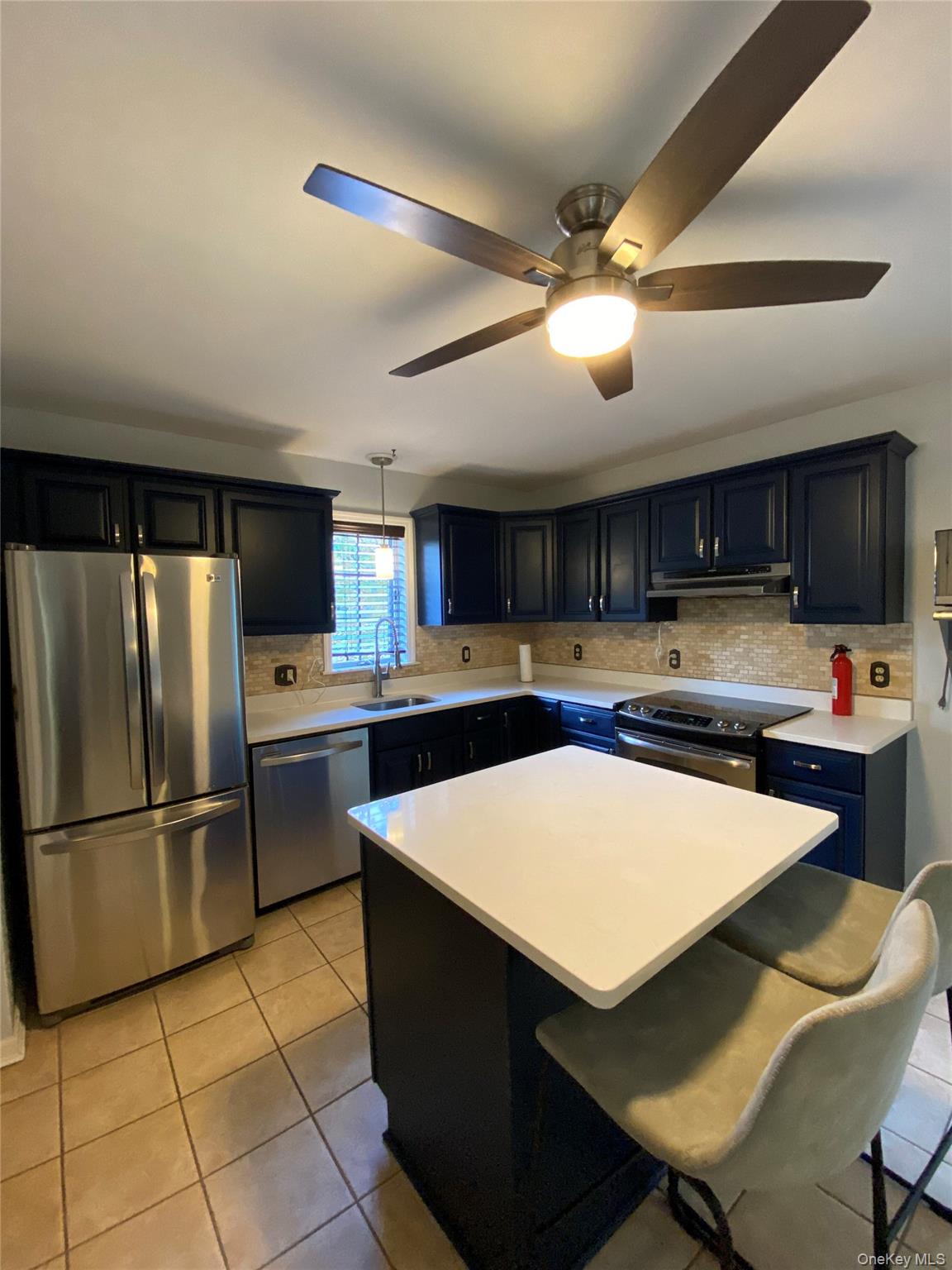 31 Denman Road Middletown, NY 10940 - Photo 6 of 18 The kitchen features dark cabinetry, stainless steel appliances, a white island countertop, and tiled flooring