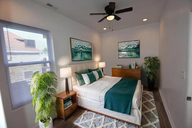 a bedroom with a bed a potted plant and a dresser