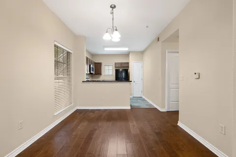 a view of a kitchen and an empty room with wooden floor