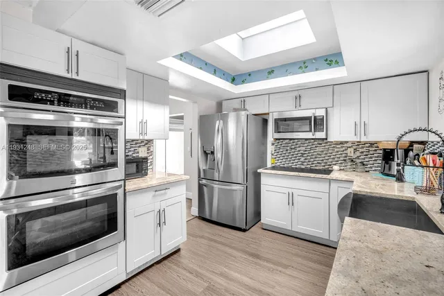 a kitchen with stainless steel appliances white cabinets and wooden floors