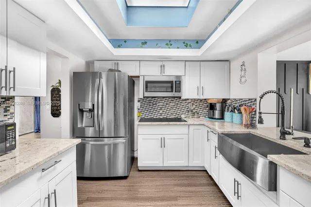 a kitchen with a refrigerator sink and white cabinets