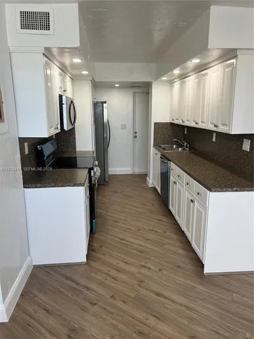 a large kitchen with stainless steel appliances kitchen island granite countertop a large counter top and wooden floors