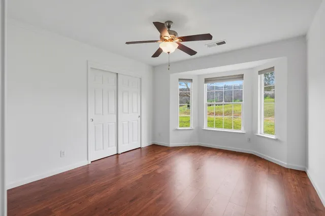 a view of empty room with wooden floor and fan