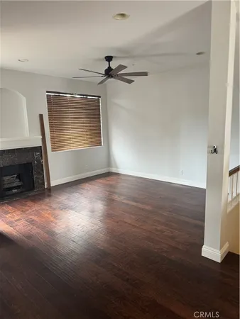 an empty room with wooden floor cabinet and windows