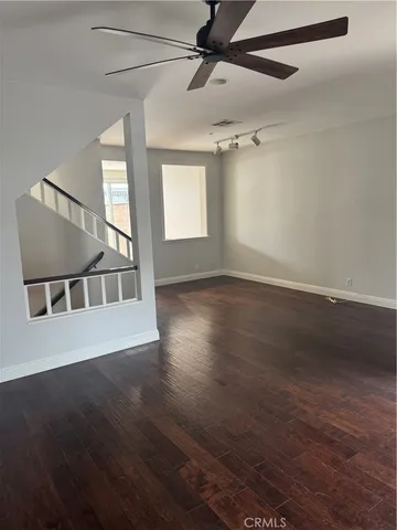 an empty room with wooden floor fan and windows