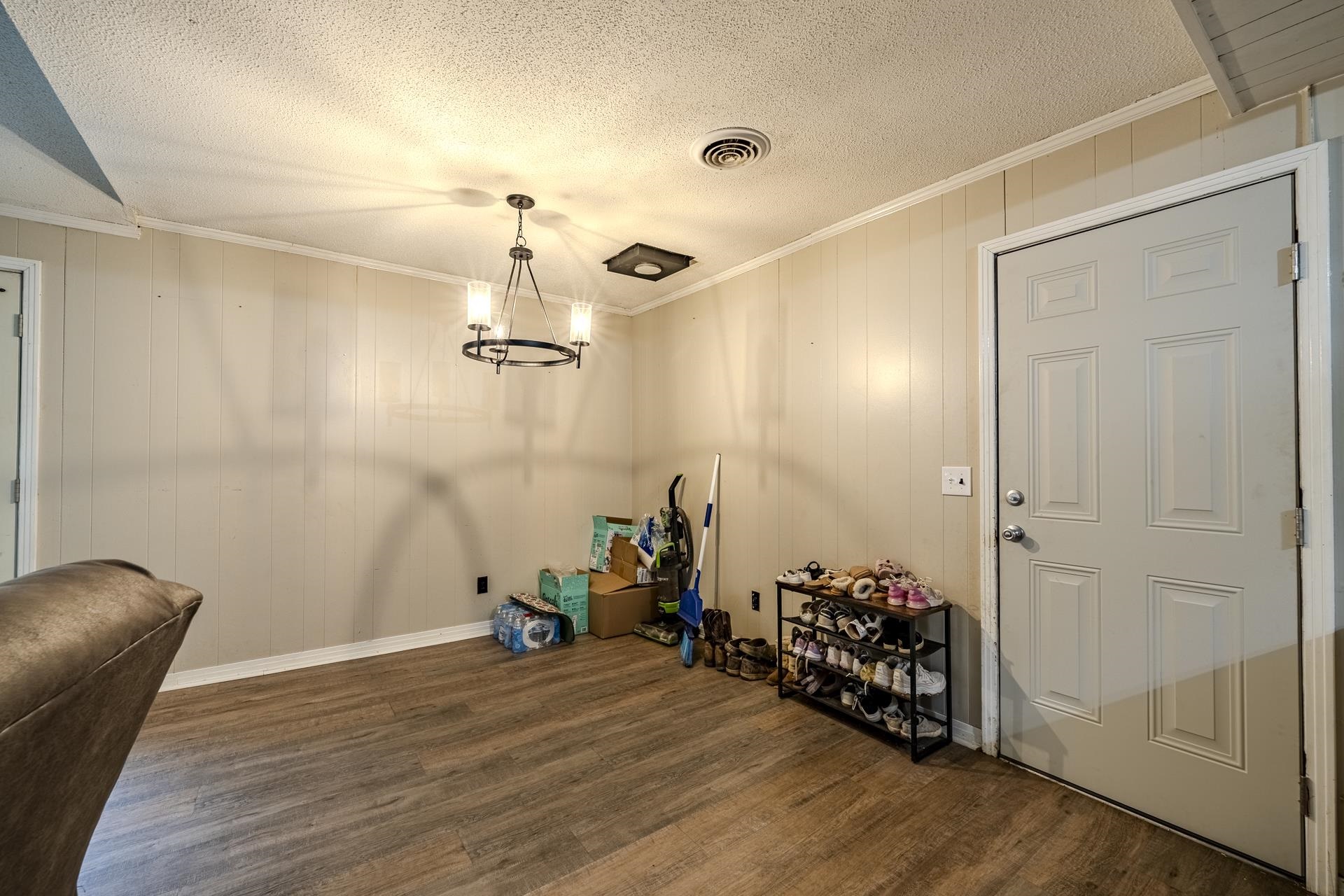 259 Oakview Drive Adamsville, TN 38310 - Photo 9 of 32 Wood-finish flooring with vertical paneling walls, crown molding, and a textured ceiling