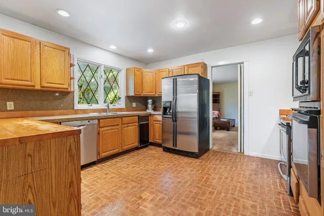 a kitchen with stainless steel appliances granite countertop a refrigerator a sink a stove with wooden cabinets