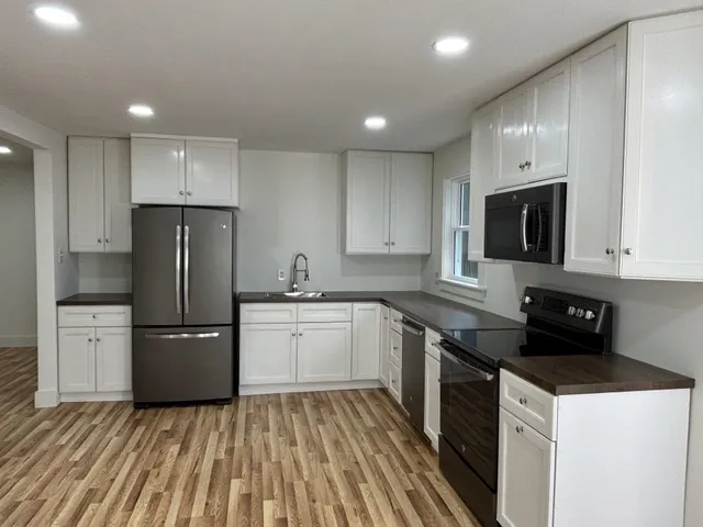 a kitchen with a sink a refrigerator a microwave and cabinets