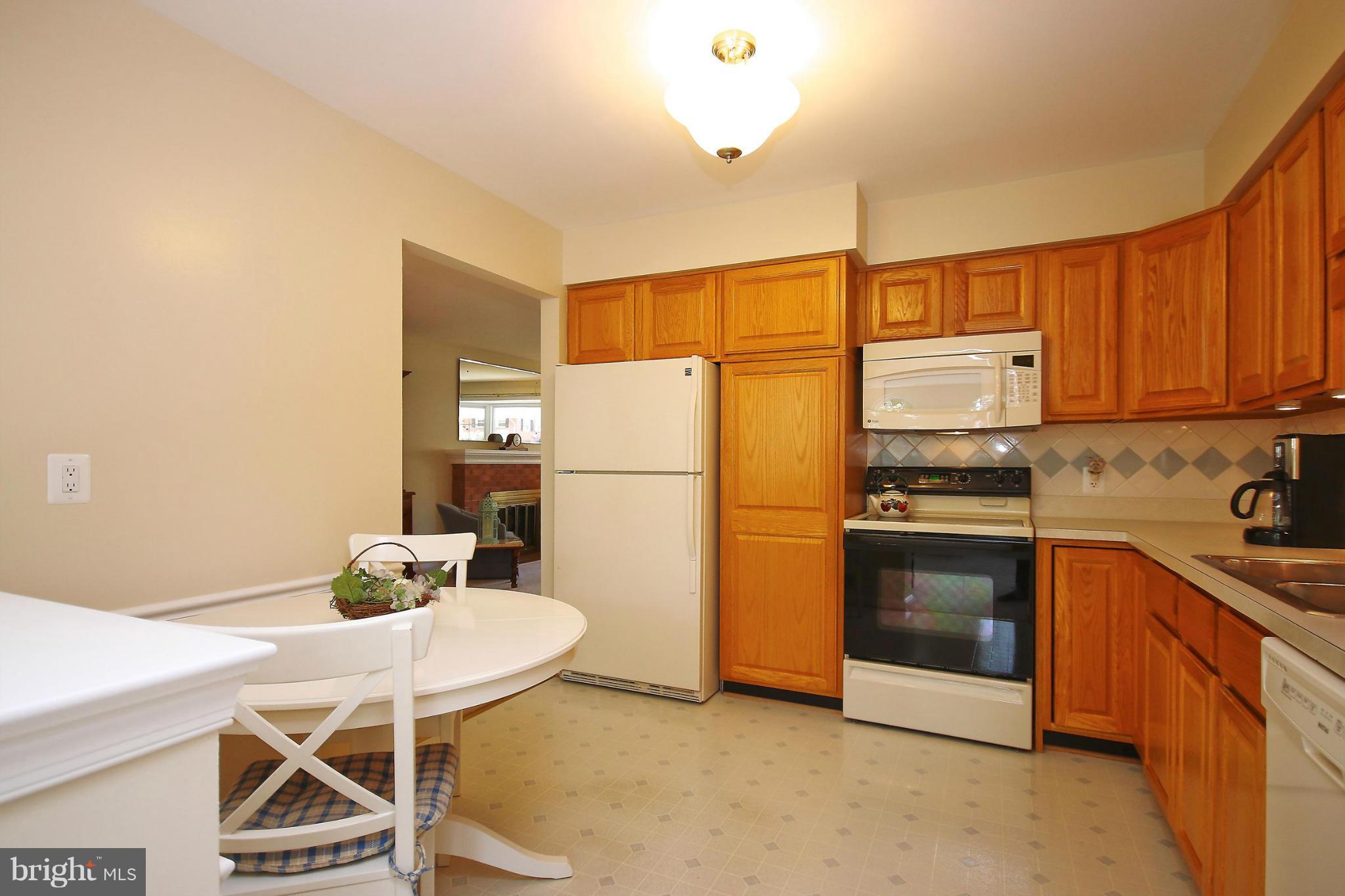 7927 Ellet Road Springfield, VA 22151 - Photo 10 of 30 a kitchen with stainless steel appliances a refrigerator a stove a sink dishwasher a dining table and chairs with wooden floor