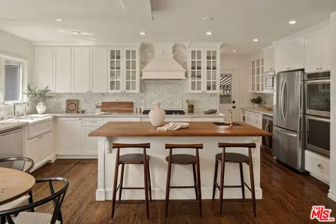 a kitchen with stainless steel appliances granite countertop a table chairs sink refrigerator and microwave