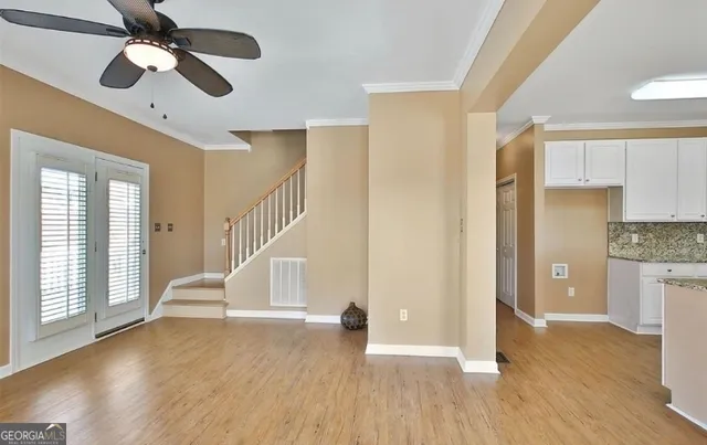 a view of empty room with wooden floor and fan