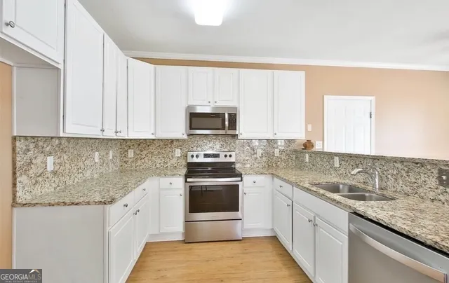 a kitchen with granite countertop white cabinets and stainless steel appliances