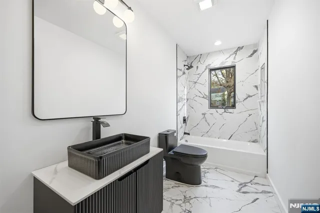 a bathroom with a bathtub sink and mirror