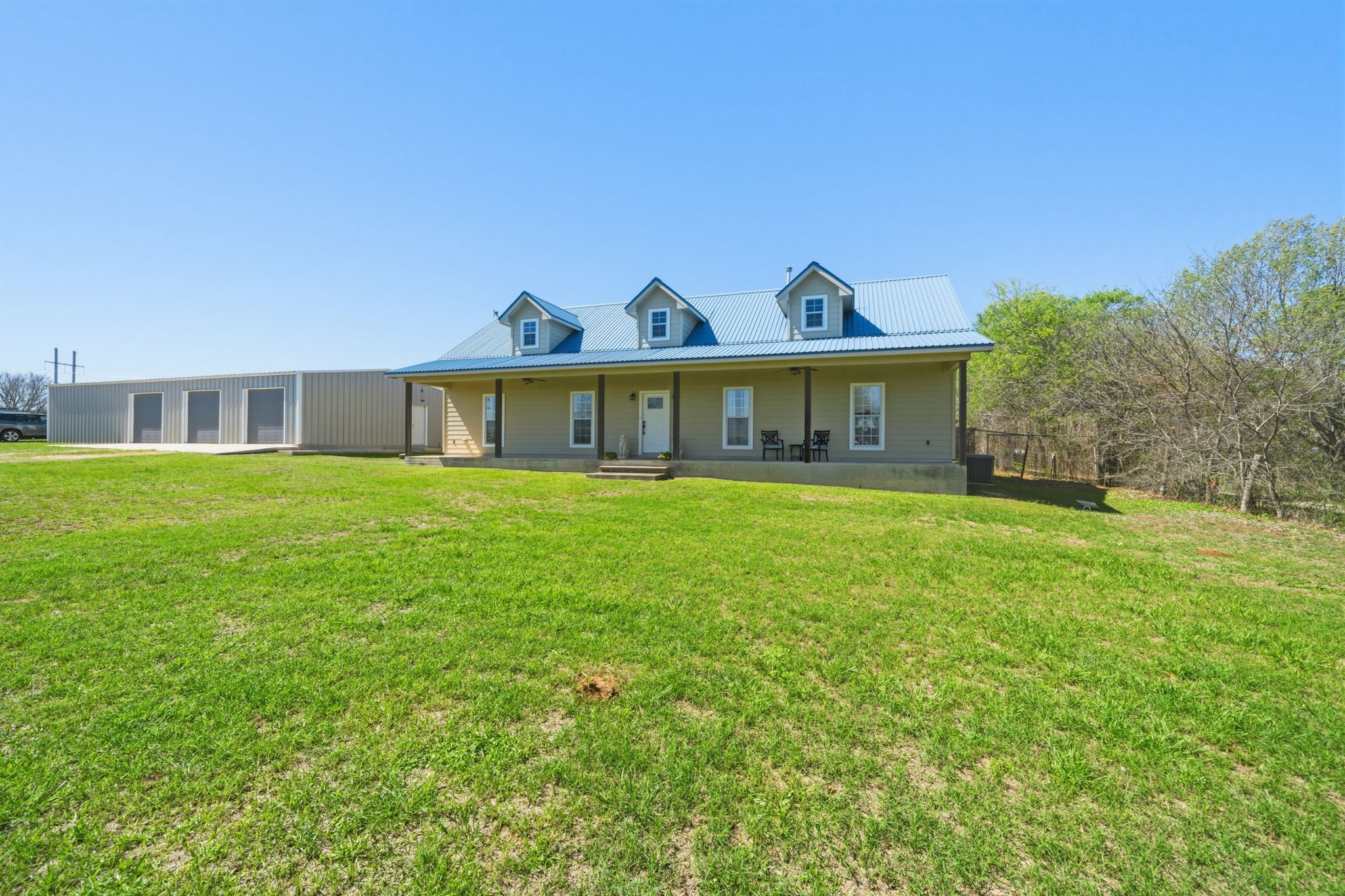 View of front facade featuring a porch, a front lawn, and a metal roof