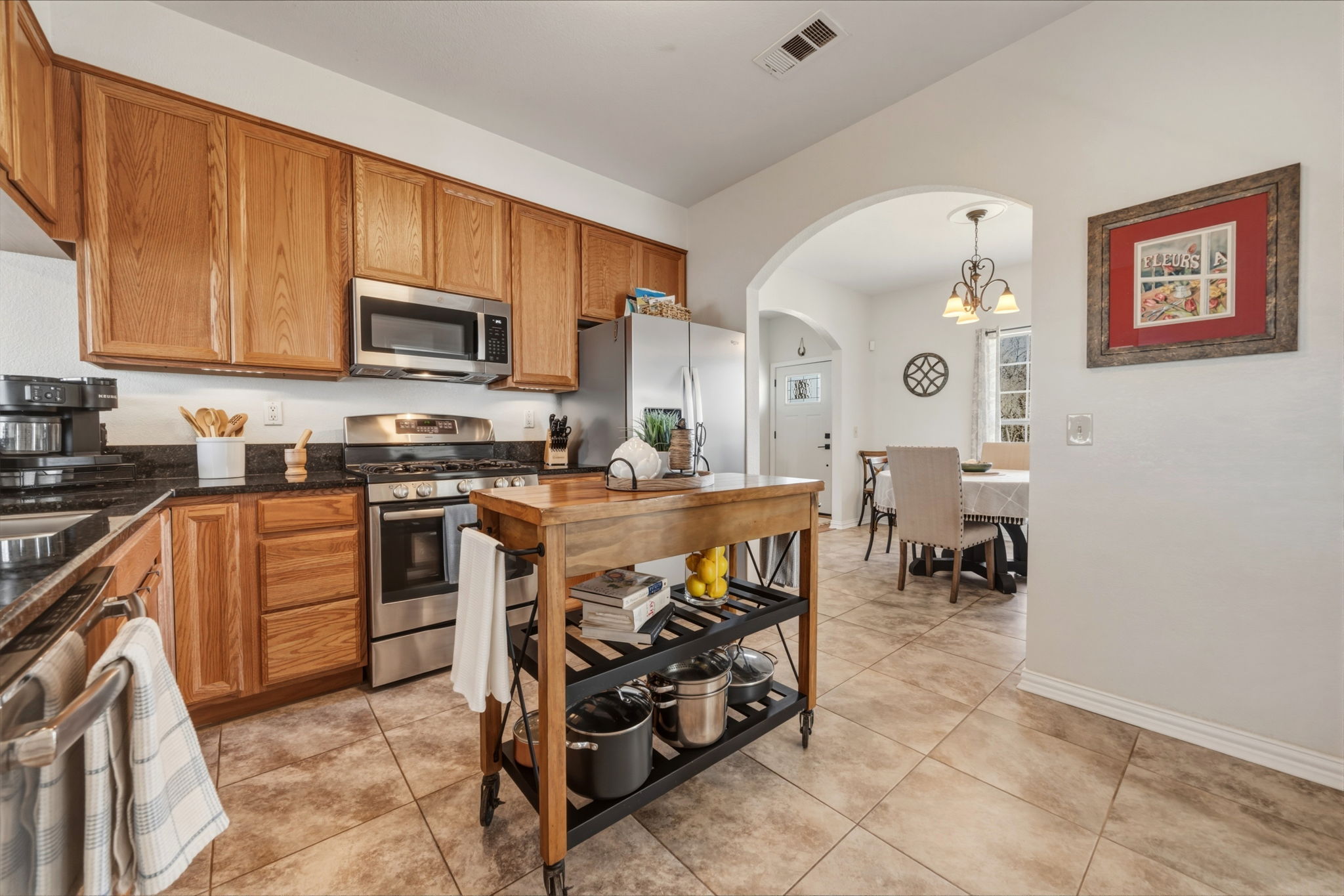 1516 Old Luling Road Lockhart, TX 78644 - Photo 4 of 39 Kitchen featuring stainless steel appliances, wood finish cabinetry, arched walkway to Formal Dining, Granite counters, and tile flooring