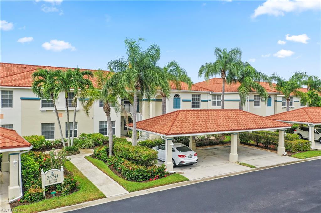 23741 Old Port Road, Unit 204 Estero, FL 34135 - Photo 21 of 46 a view of a patio with table and chairs under an umbrella