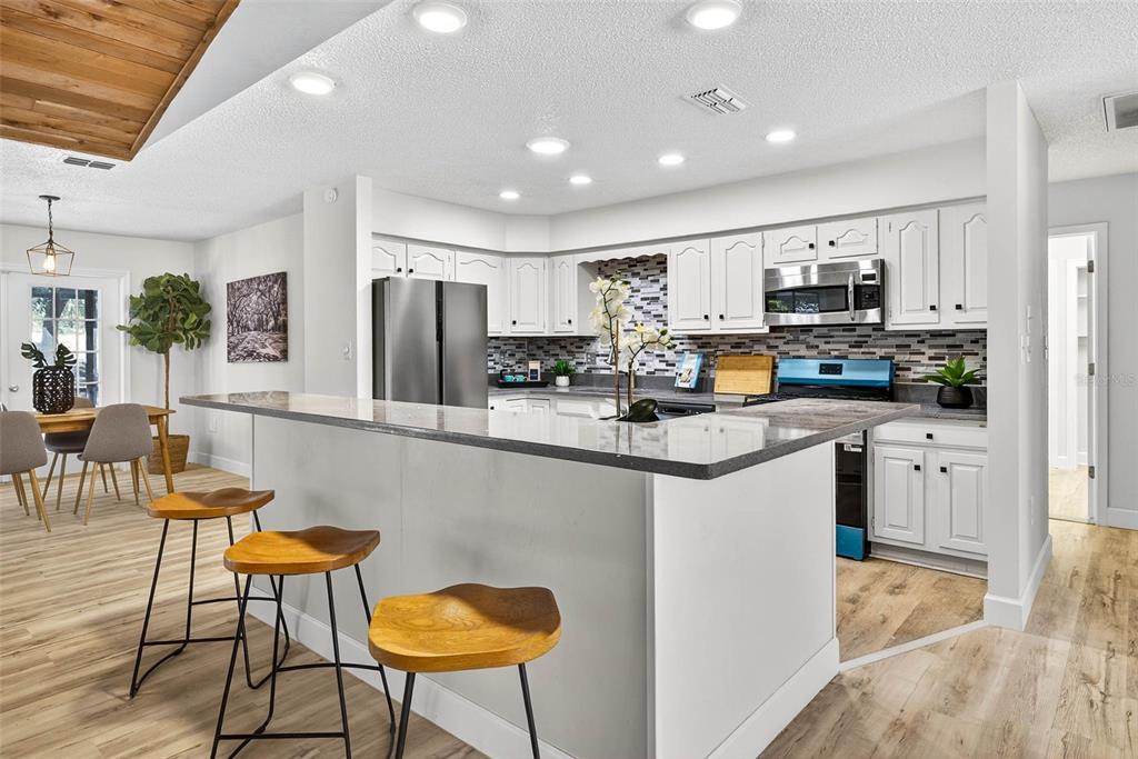 14252 Trinity Road Brooksville, FL 34614 - Photo 8 of 26 a kitchen with stainless steel appliances kitchen island granite countertop a table chairs and a refrigerator