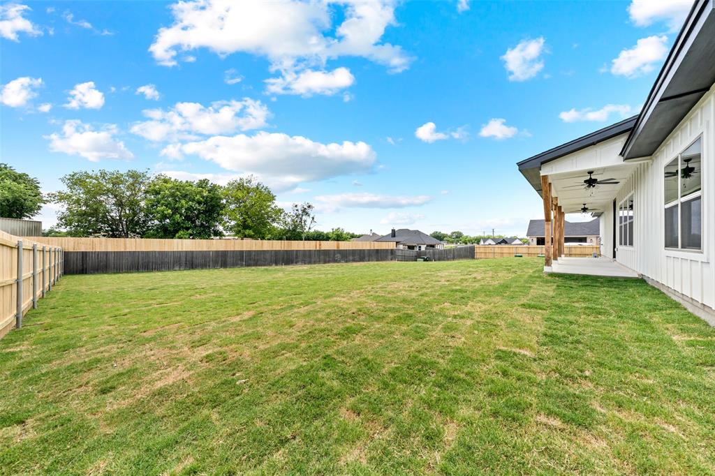 138 Dana Pt Road Lorena, TX 76655 - Photo 22 of 24 Spacious backyard featuring a wood privacy fence, expansive lawn, covered patio, wood-wrapped structural columns, and two ceiling fans