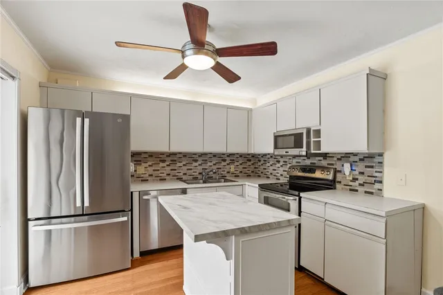 a kitchen with stainless steel appliances a stove a refrigerator a sink and white cabinets