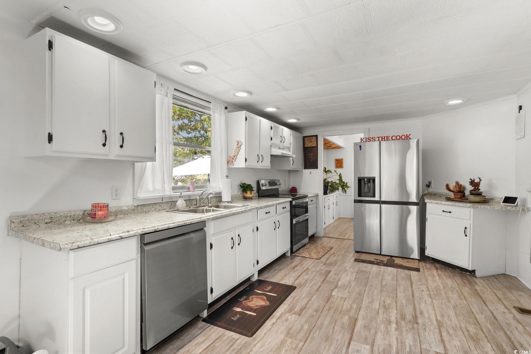 125 Moultrie Court Murrells Inlet, SC 29576 - Photo 10 of 40 Kitchen featuring appliances with stainless steel finishes, light wood-style flooring, white cabinetry, recessed lighting, and under cabinet range hood