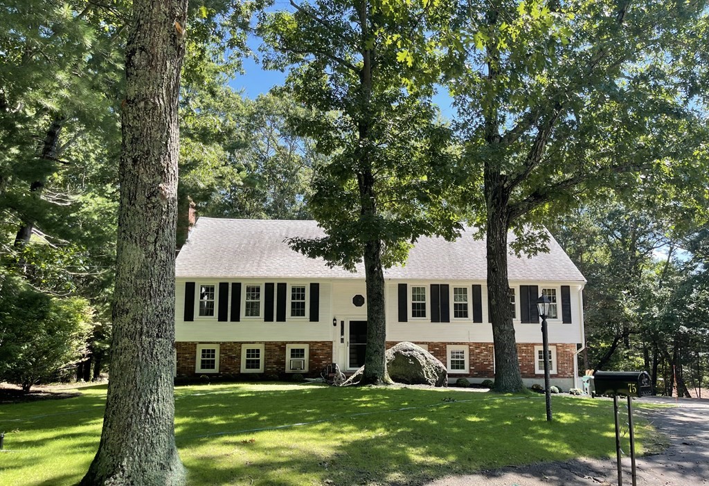 a front view of a house with a garden and trees