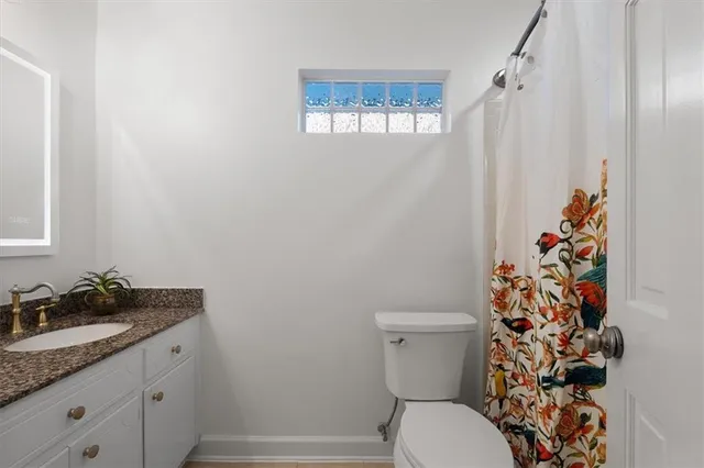 a bathroom with a granite countertop toilet and a sink a mirror