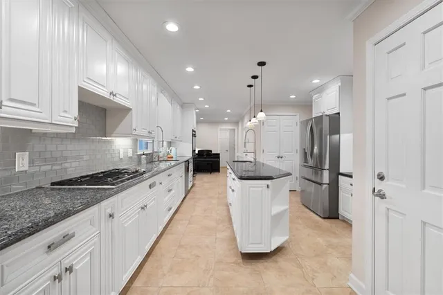 a large kitchen with stainless steel appliances kitchen island granite countertop a refrigerator and a stove top oven