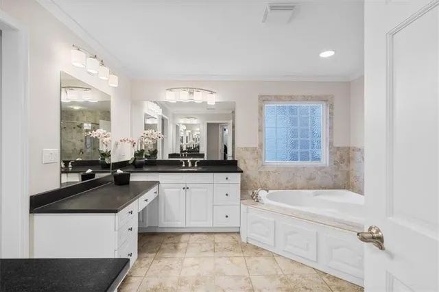 a spacious bathroom with a granite countertop sink a mirror a bathtub and window