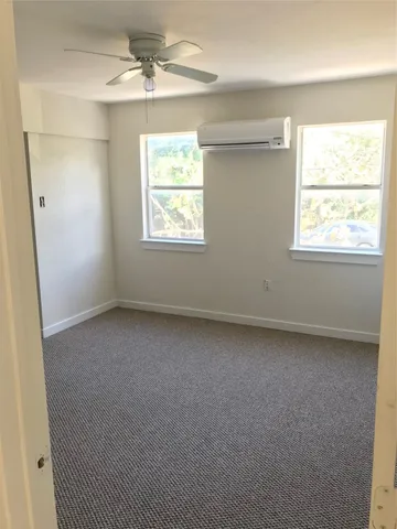 an empty room with a window and a fan