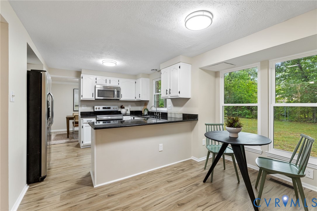 9808 Brenspark Road Chesterfield, VA 23832 - Photo 5 of 28 a kitchen with stainless steel appliances granite countertop a stove top oven a sink dishwasher a dining table and chairs with wooden floor
