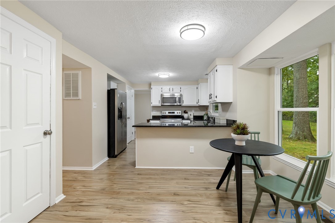 9808 Brenspark Road Chesterfield, VA 23832 - Photo 7 of 28 a kitchen with stainless steel appliances granite countertop a refrigerator a sink a stove a dining table and chairs with wooden floor