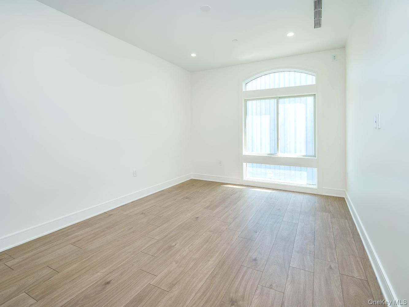 24 Lumber Road, Unit 1 Roslyn, NY 11576 - Photo 15 of 18 an empty room with wooden floor and windows