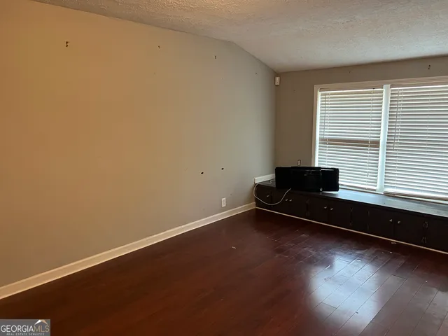 a bench sitting in wooden floor next to a window