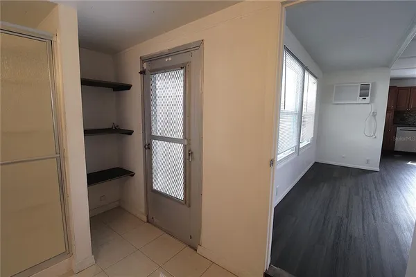 a view of an empty room with a window and wooden floor