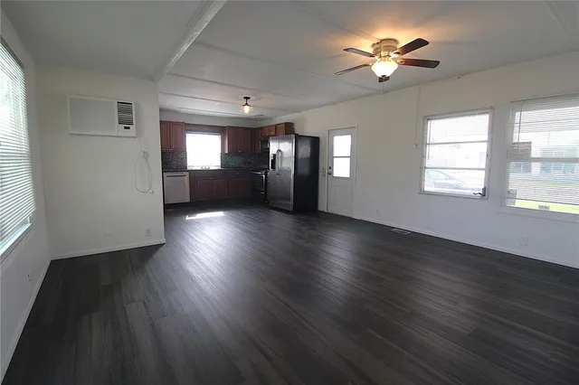 a view of an empty room with a window and wooden floor
