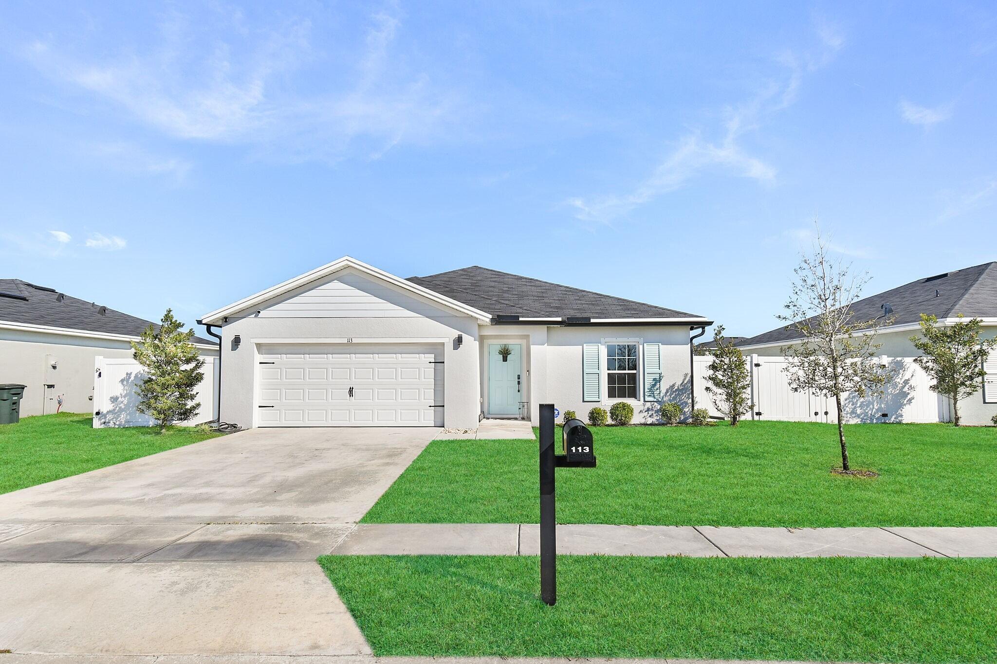 113 Dabou Loop Belle Glade, FL 33430 - Photo 2 of 22 a front view of a house with a yard and trees
