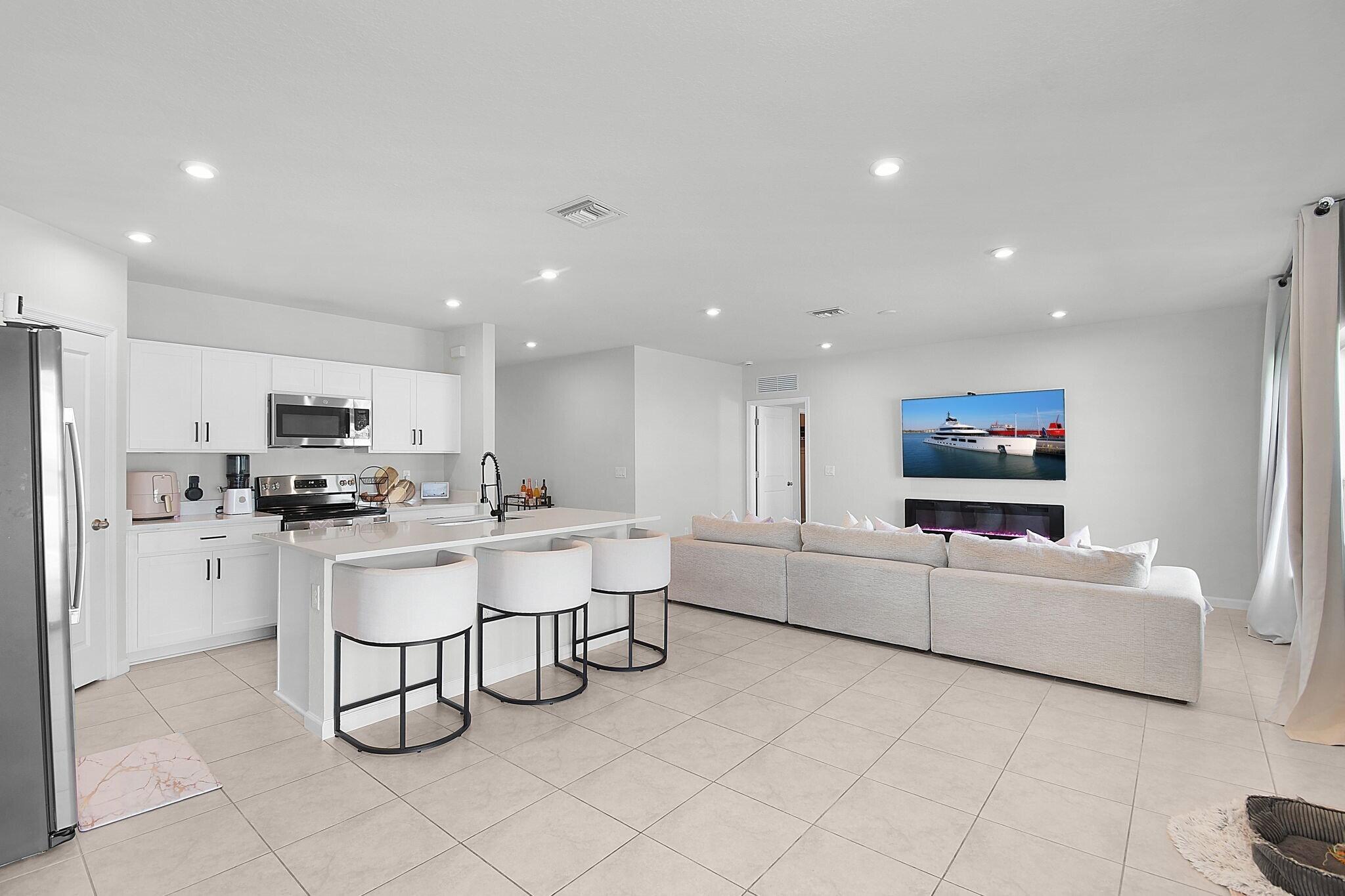 113 Dabou Loop Belle Glade, FL 33430 - Photo 8 of 22 a living room with furniture a flat screen tv and kitchen view