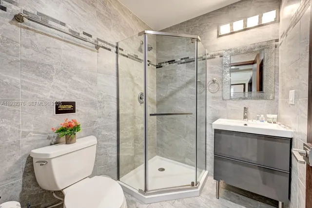 a bathroom with a shower sink mirror and toilet