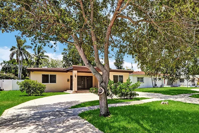 a front view of a house with a yard and trees