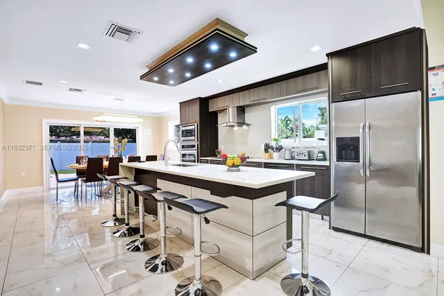 a kitchen with stainless steel appliances granite countertop a table chairs and a refrigerator