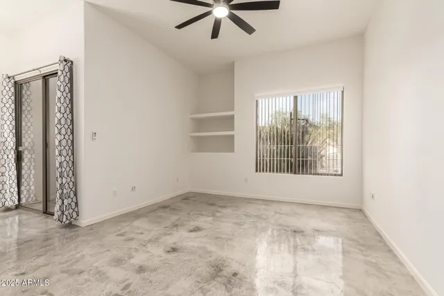 an empty room with fan and windows