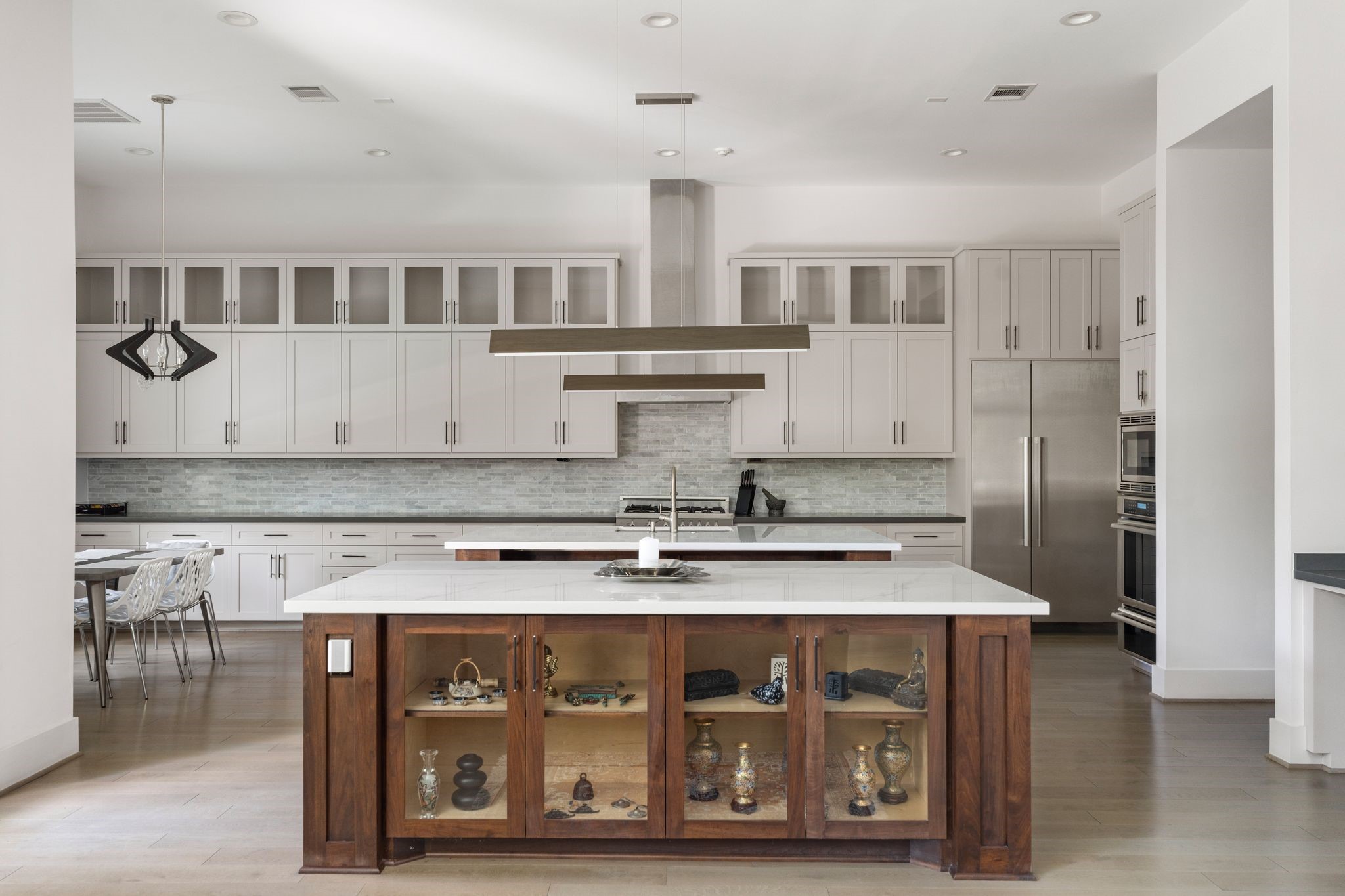 5427 Maple Street Houston, TX 77096 - Photo 3 of 46 The kitchen spans the width of the home, with two oversized islands, beautiful cabinetry, a full tile backsplash, and a stainless vent hood as the centerpiece.